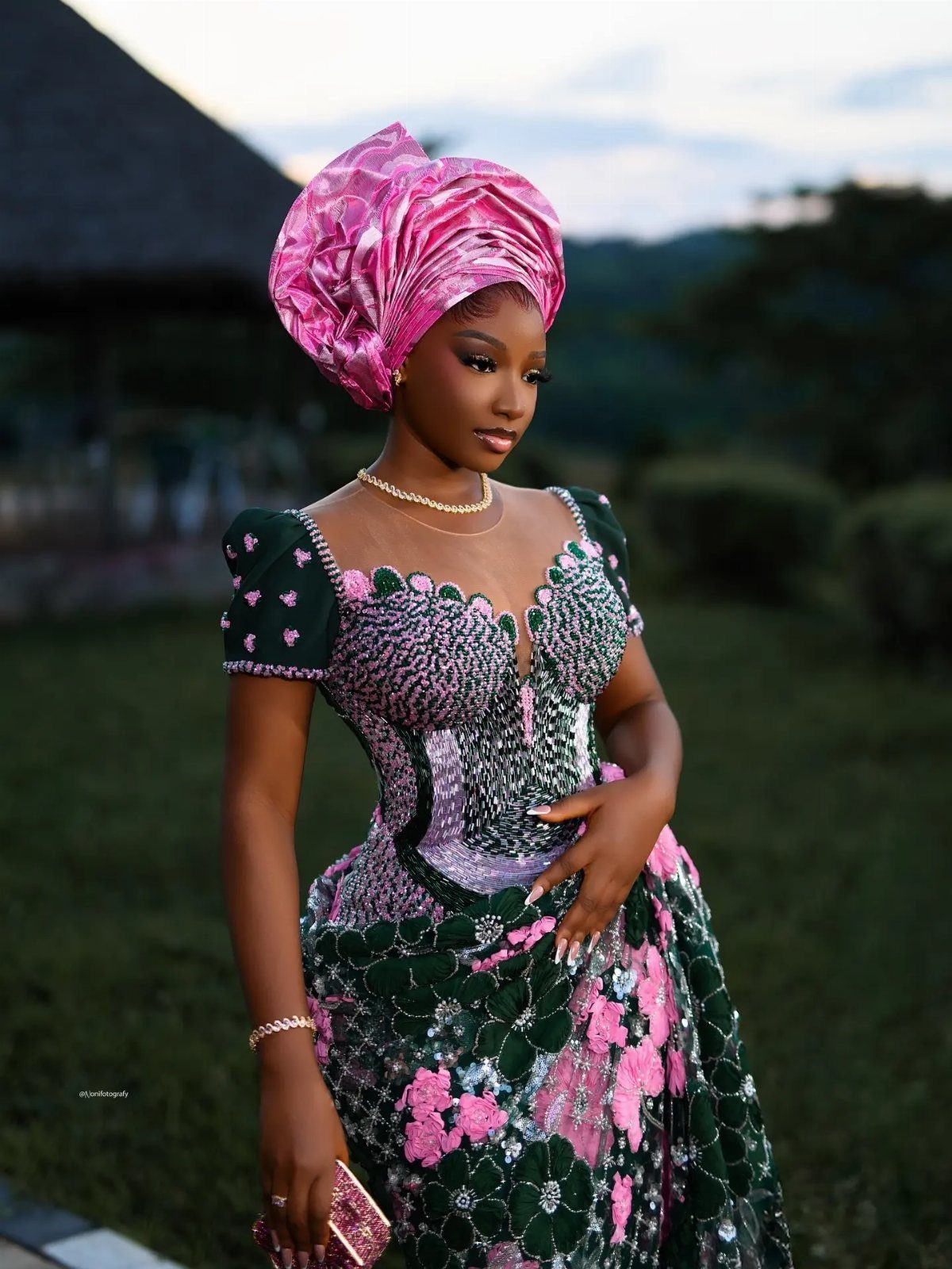 Woman in a green and pink embellished African bridal dress and pink headwrap.