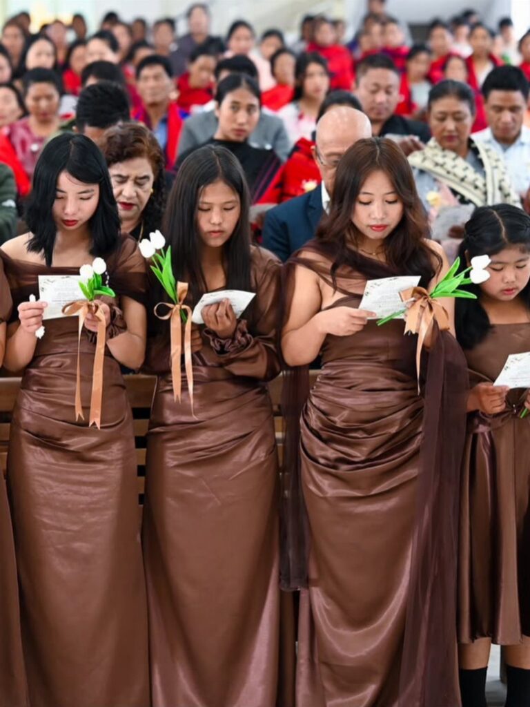 Four women in long brown satin bridesmaids dresses holding white tulips and cards.