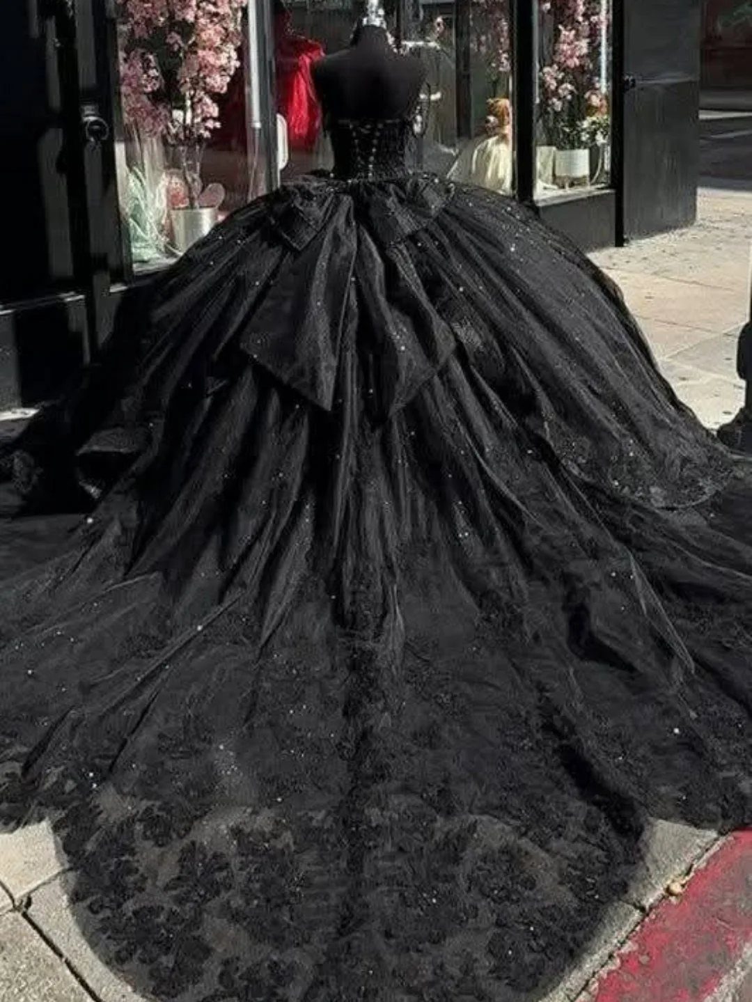 Voluminous black ballgown wedding dress with corset bodice and bow on a mannequin.