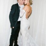 Hailey Bieber and Justin Bieber kissing, featuring her off-the-shoulder lace wedding dress.