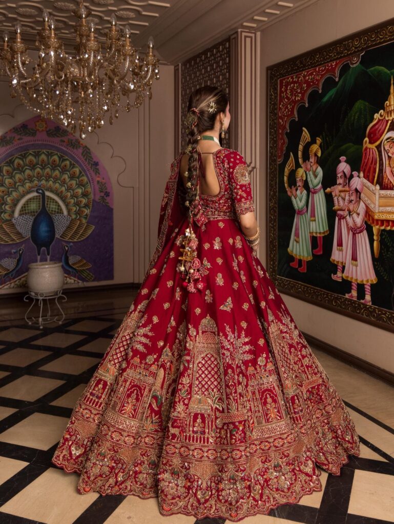 Woman wearing a red and gold embroidered Indian wedding lehenga in a palace room