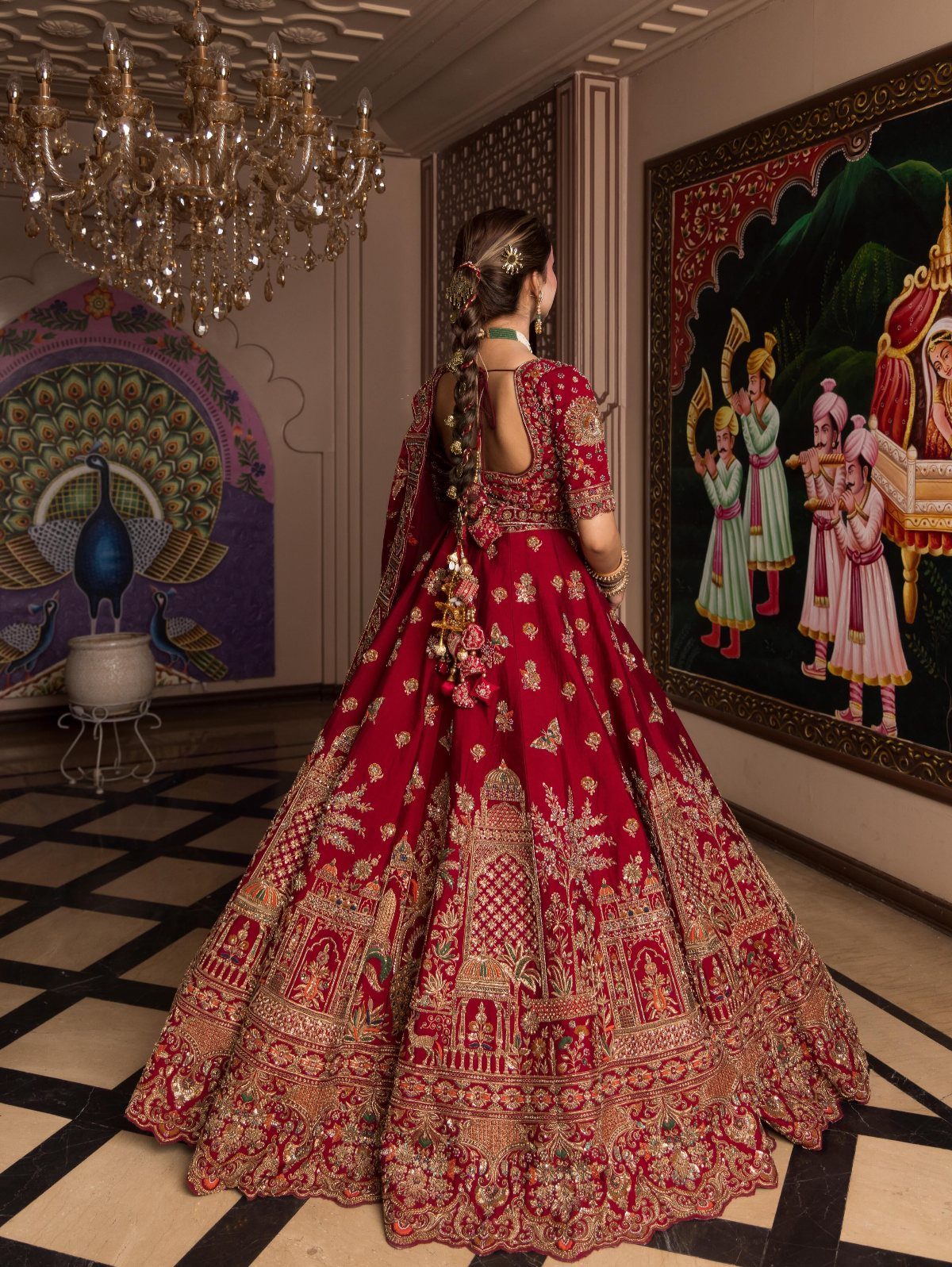 Woman wearing a red and gold embroidered Indian wedding lehenga in a palace room