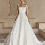 Woman in a white sleeveless jacquard wedding gown with a full voluminous skirt.