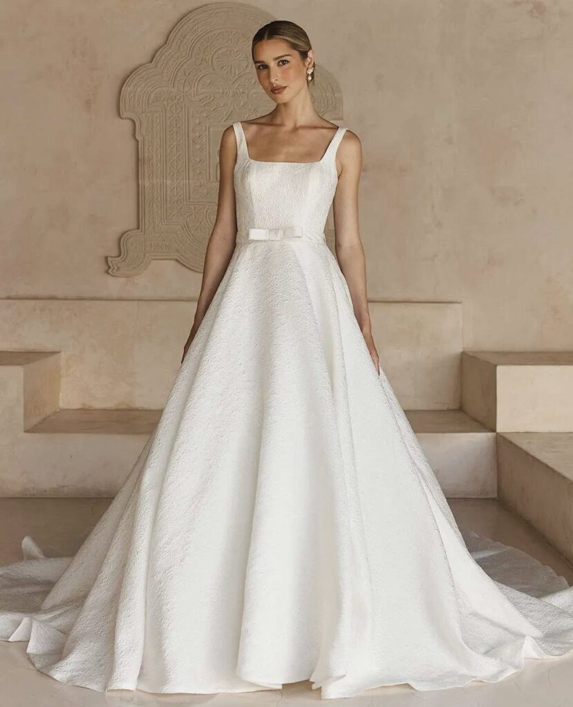 Woman in a white sleeveless jacquard wedding gown with a full voluminous skirt.