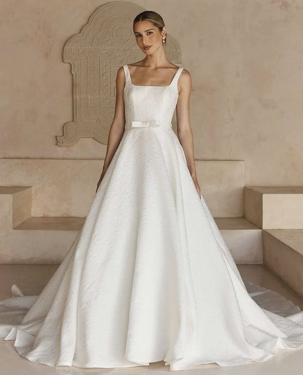 Woman in a white sleeveless jacquard wedding gown with a full voluminous skirt.