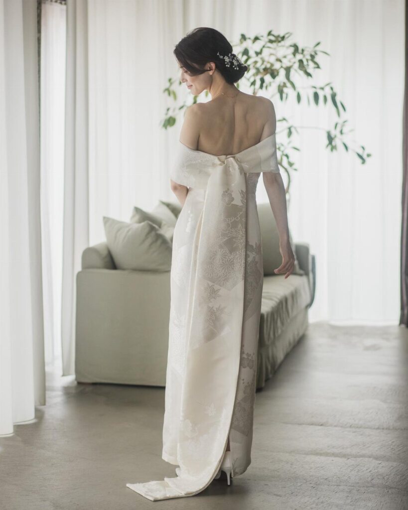 Woman from behind wearing a white Japanese style wedding gown in a bright room