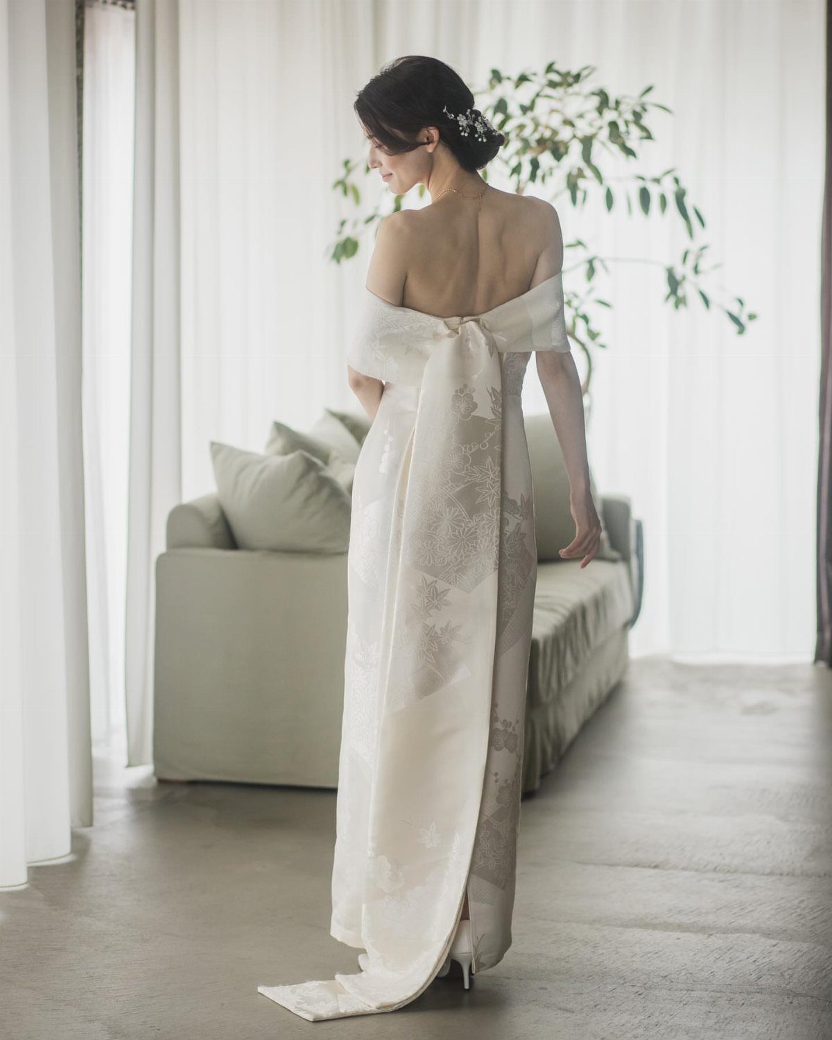 Woman from behind wearing a white Japanese style wedding gown in a bright room