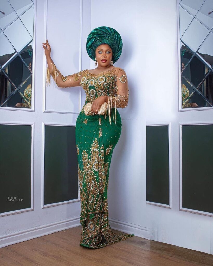 Woman in a green and gold Nigerian wedding dress with a matching gele headtie.