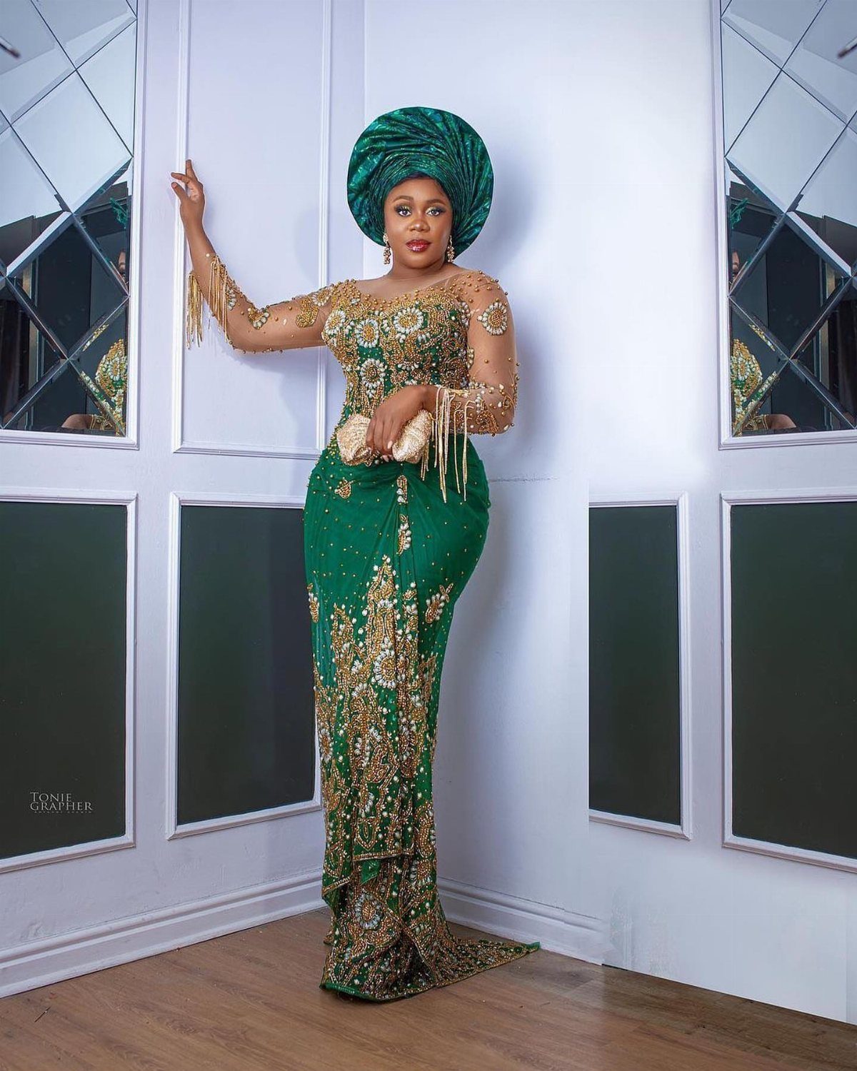 Woman in a green and gold Nigerian wedding dress with a matching gele headtie.