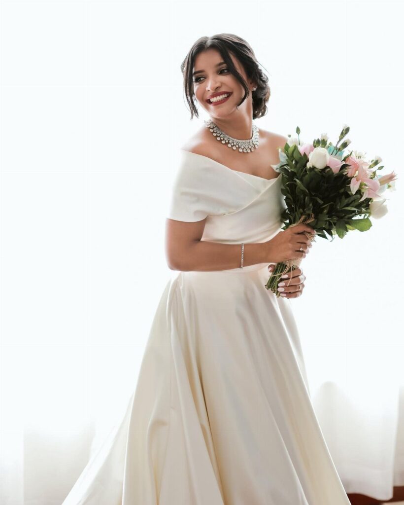 Woman in a white satin bridal gown holding a floral wedding bouquet