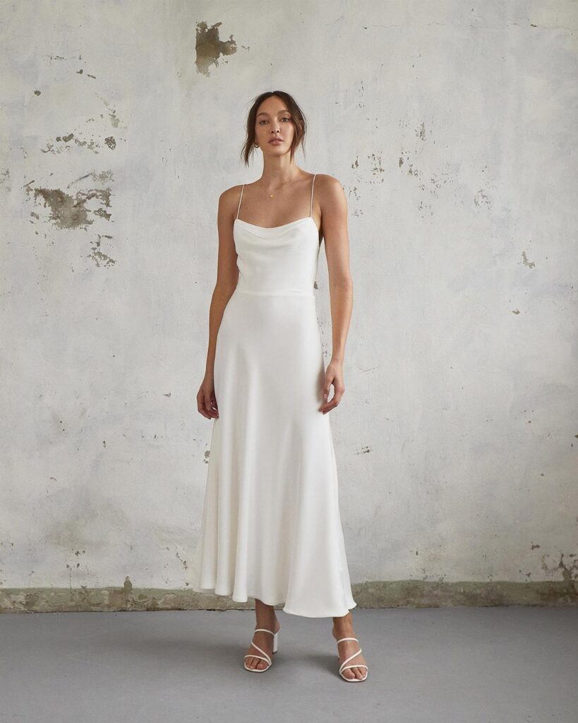 Woman wearing a long white silk wedding dress with a cowl neckline