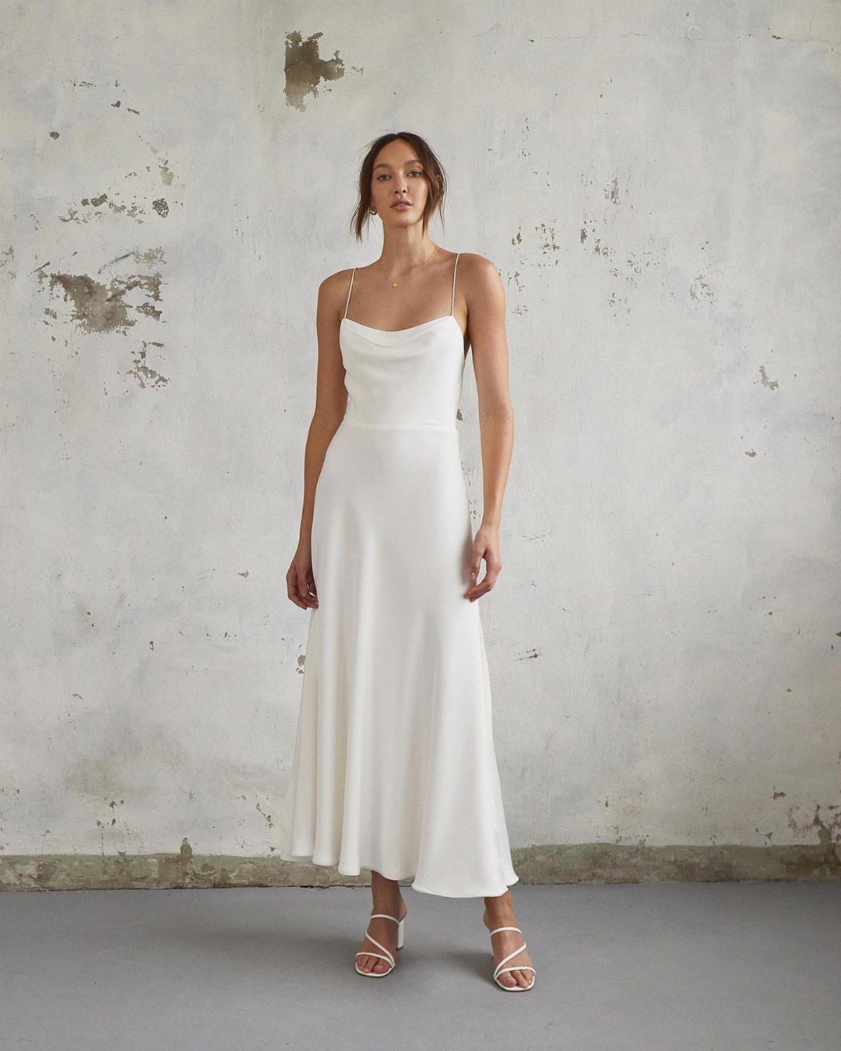 Woman wearing a long white silk wedding dress with a cowl neckline