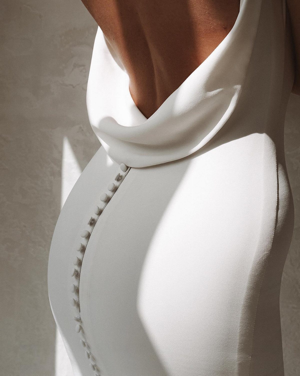 White silk wedding gown with a draped cowl back and button details.