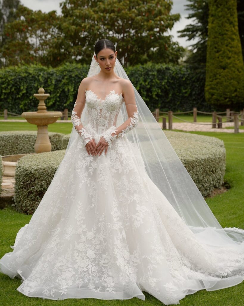 Woman in a white lace wedding dress and veil standing in a garden