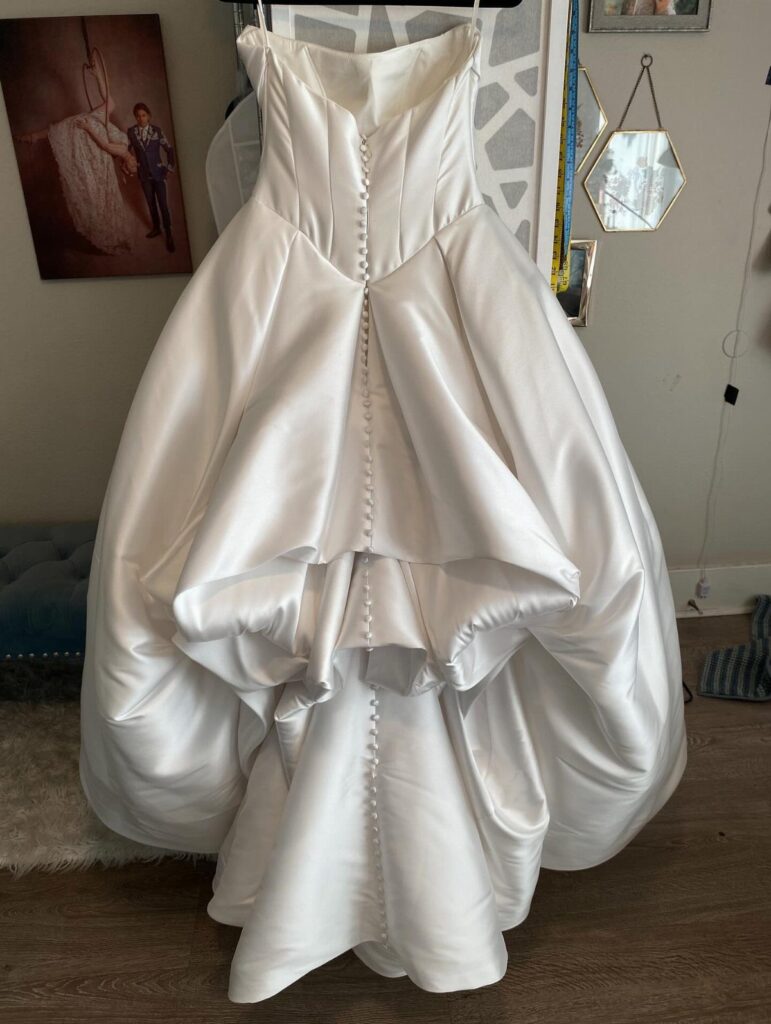 White satin wedding dress with a French bustle tucked under the train.