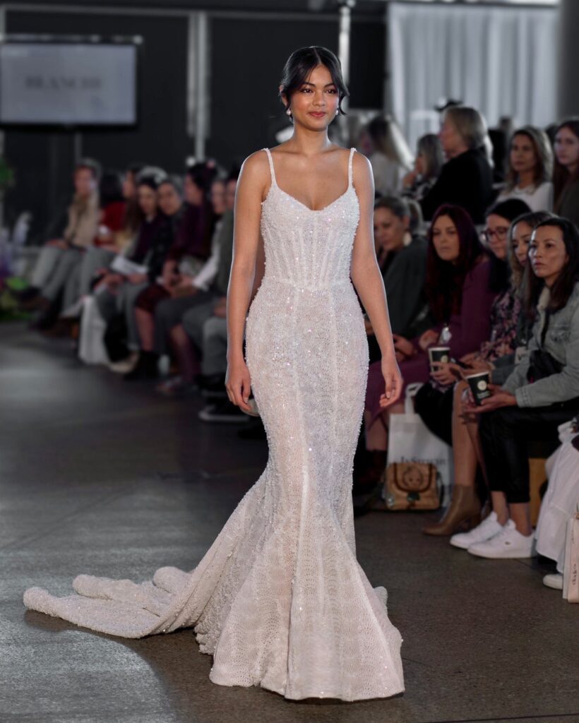 Model wearing a beaded white couture wedding gown walking a fashion runway