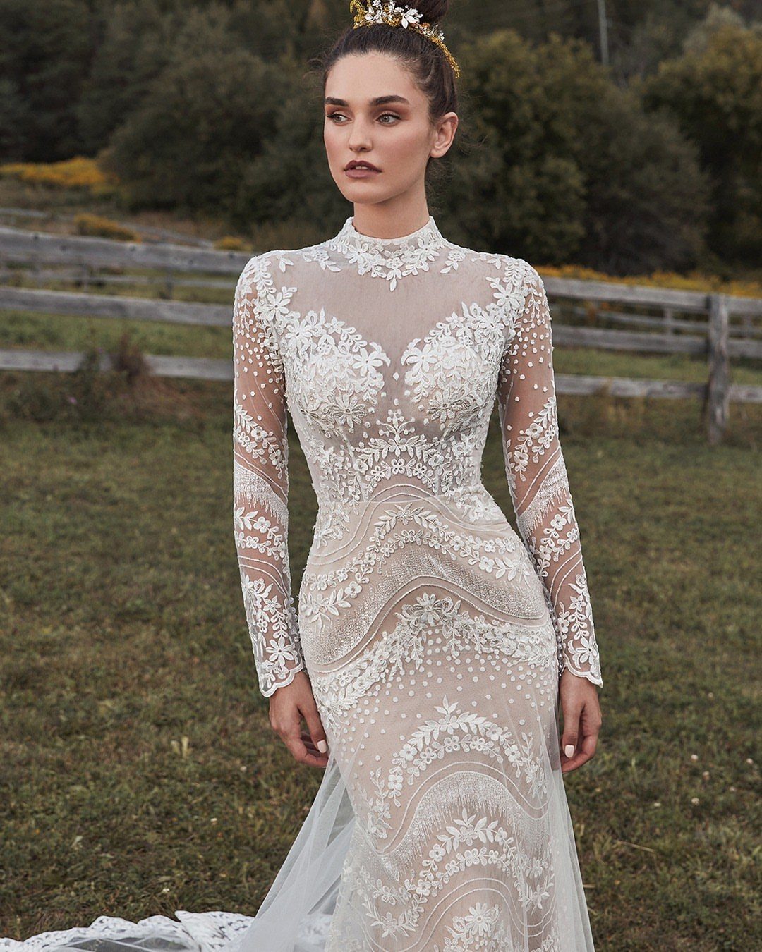 Woman in a white long-sleeved wedding dress with lace overlays in a field