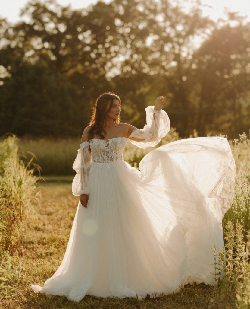 Woman in a flowy white wedding dress with lace bodice in a sunny field