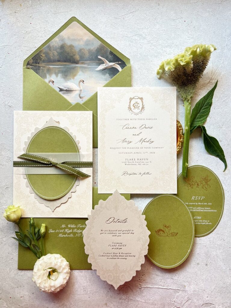 Wedding invitation suite in sage green and cream with floral accents and swan envelope.