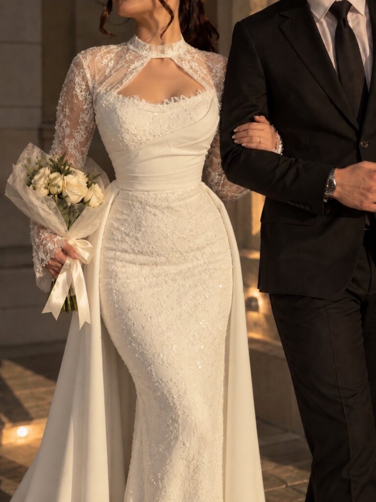 Woman in a white lace wedding dress with a cape holding white roses